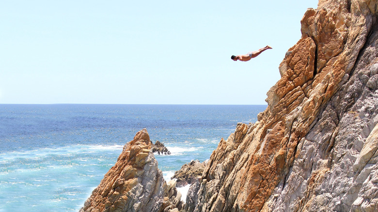 Person cliff diving past rocks