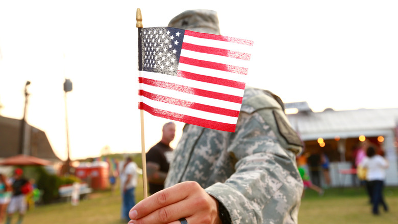 Soldier holding up flag to camera