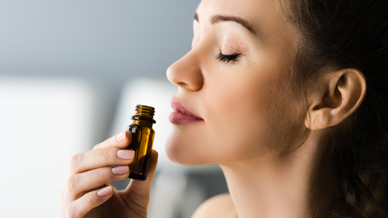 woman smelling essential oil bottle