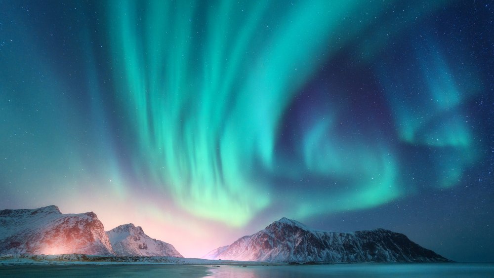 Green and purple aurora borealis over snowy mountains. Northern lights in Lofoten islands, Norway. Starry sky with polar lights. Night winter landscape with aurora, high rocks, beach. Travel. Scenery🔍