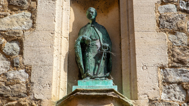 Green bronze statue of st. clement with anchor in masonry alcove