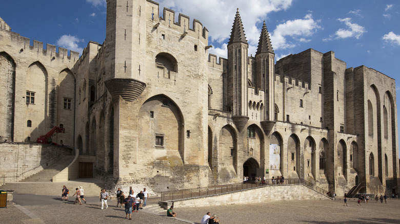 Exterior of palais des papes in avignon on sunny day with tourists