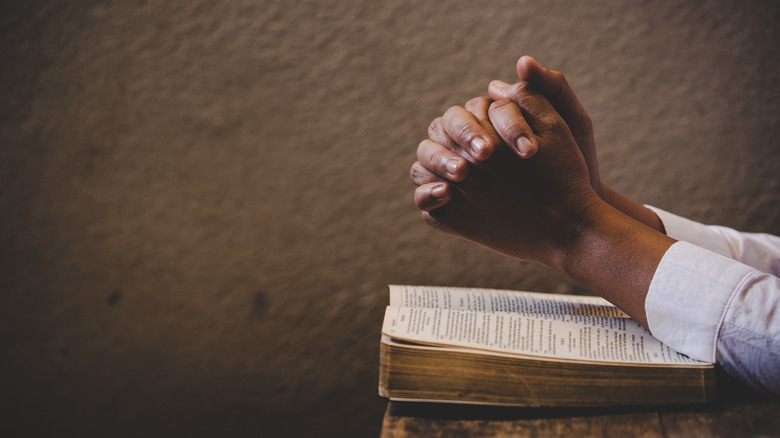 clasped hands over Bible