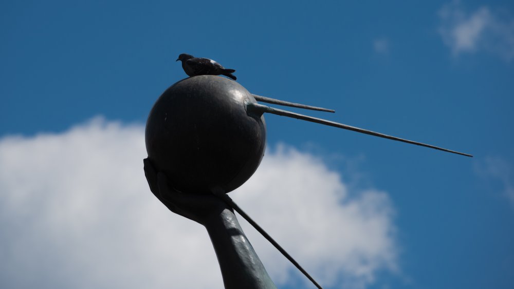 A statue of a person holding the Sputnik satellite.