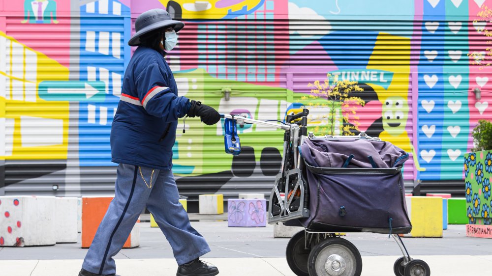 A post-person delivering the post in a face mask and an incongruously jolly backdrop.