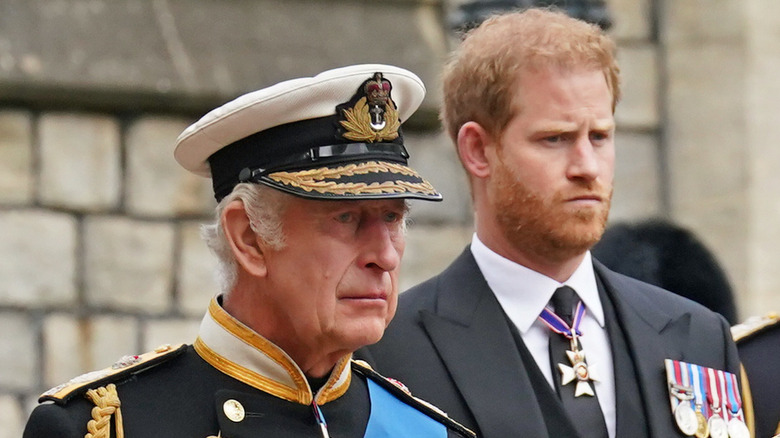 Charles III walks ahead of Prince Harry