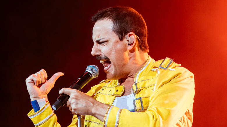 Freddie Mercury onstage singing in yellow jacket