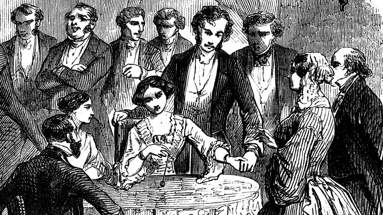 Spiritualist meeting in a Paris drawing room, 1853. Communicating with the 'other side' by means of the hat, table-turning, and the pendulum
