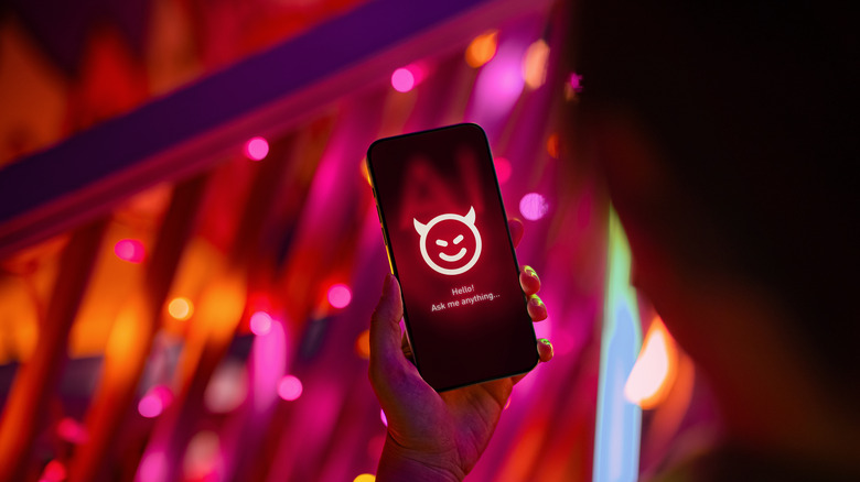 A woman holding a smartphone displaying a devil smiley face