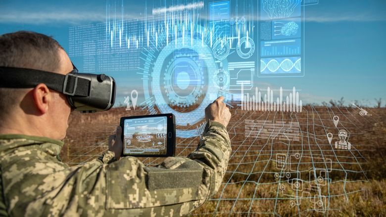 Soldier in a field wearing a VR headset and pointing at projected images