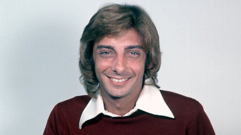 Barry Manilow smiling in red cardigan in the 1970s