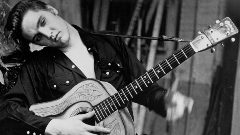 Elvis Presley standing holding guitar