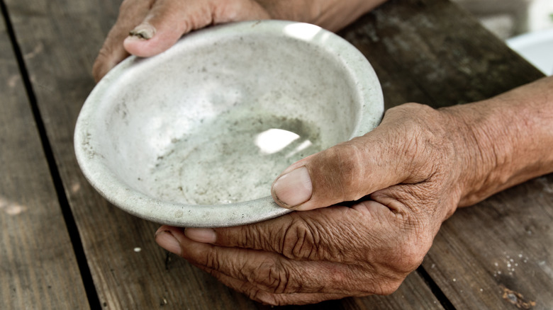 poor man holds empty plate