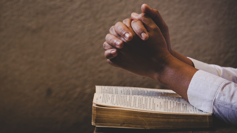 hands folded on bible