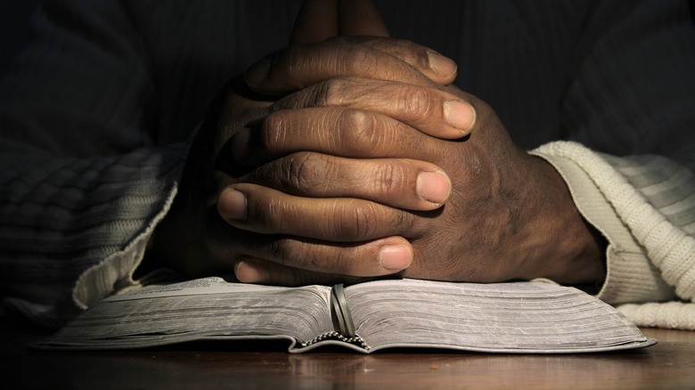 folded hands on a bible