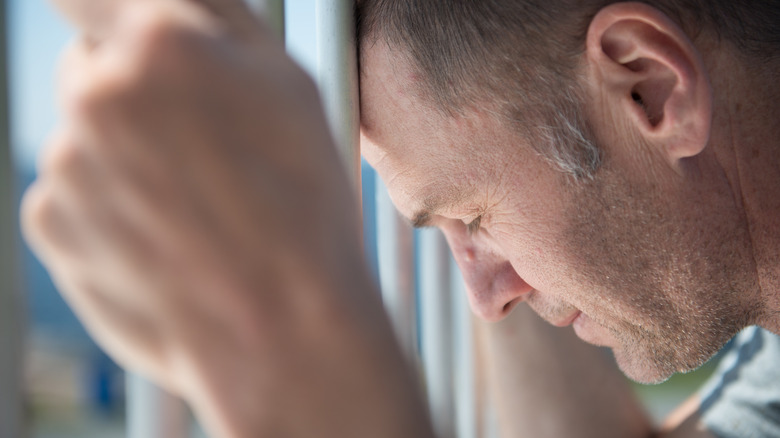 man with head on prison cell bars