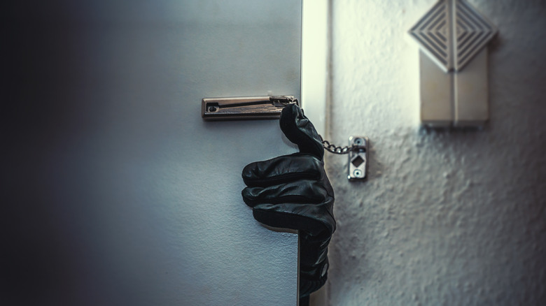 gloved hand of intruder in door