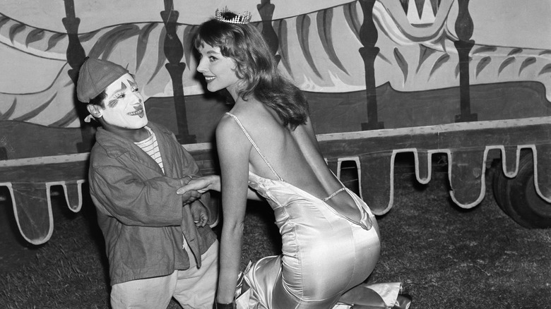 Vikki Dougan posing with a circus clown, 1957