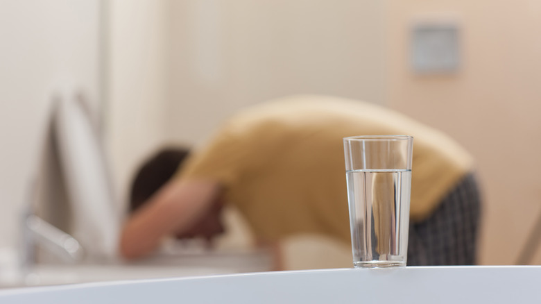 Guy vomiting into toilet