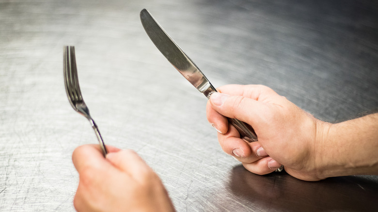 hands holding knife and fork