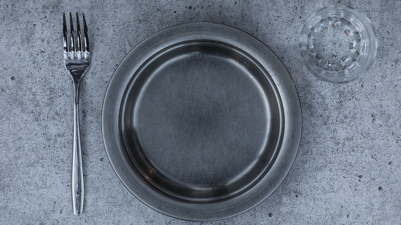 fork and empty plate on concrete