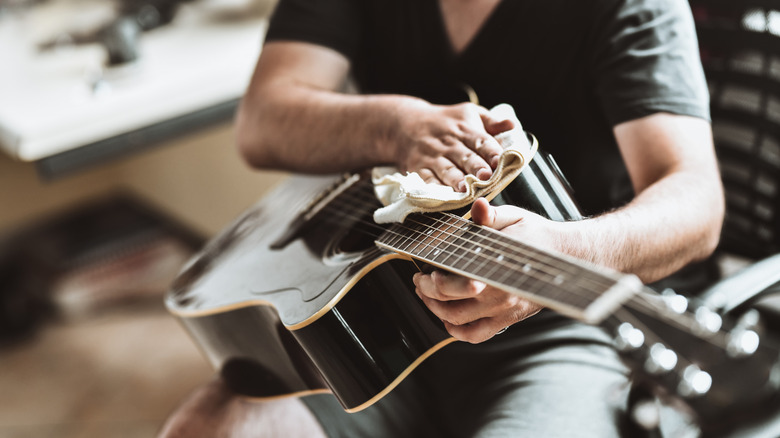 Guy cleaning guitar with rag