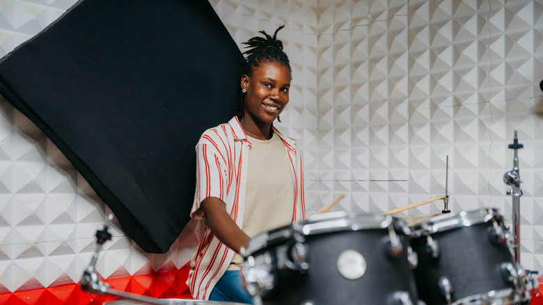 Young woman sitting at a drum kit holding drumsticks