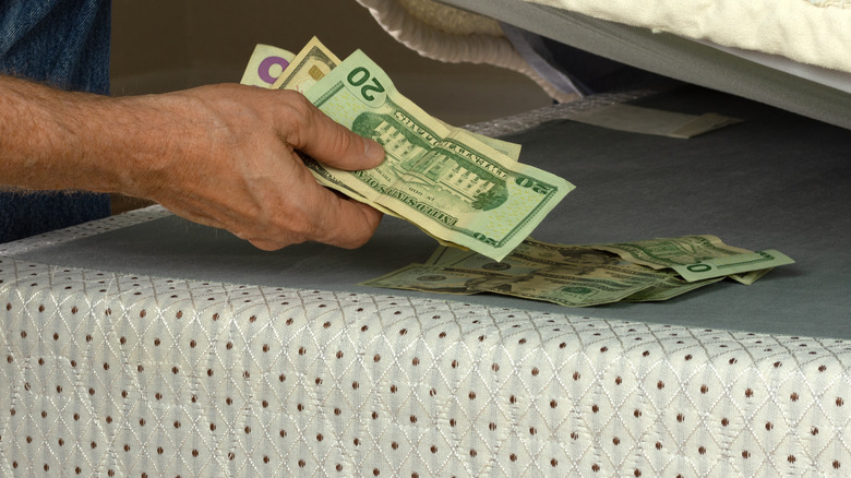 Hand putting money under mattress