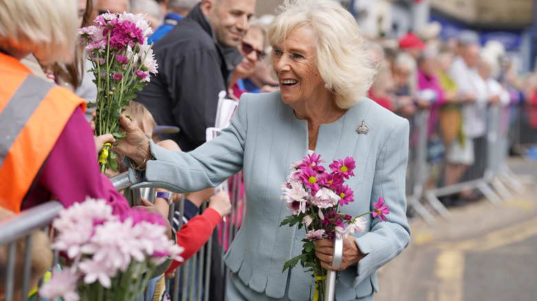 Queen Camilla greeting people holding flowers