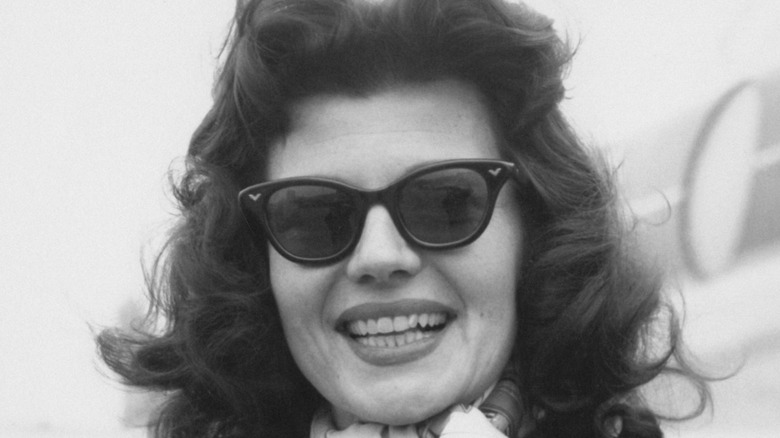 Rita Hayworth smiles in sunglasses