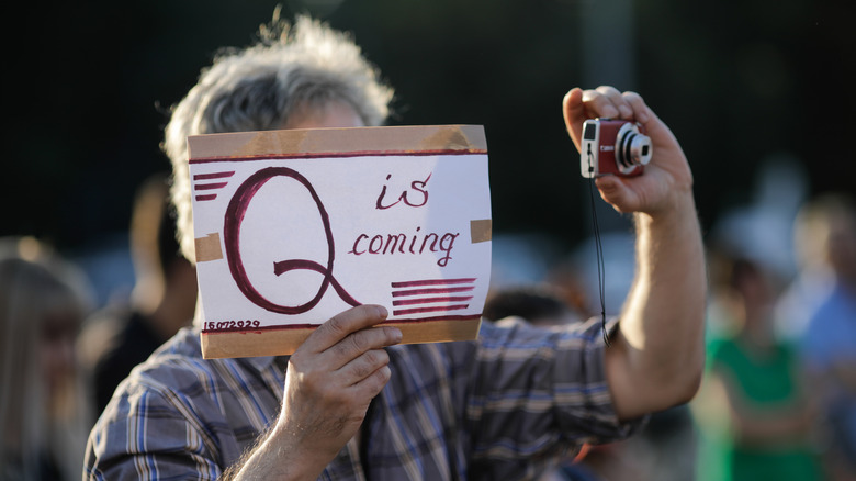 A man holding a QAnon related sign