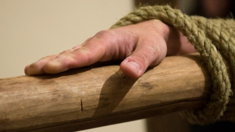 man's hand bound with rope