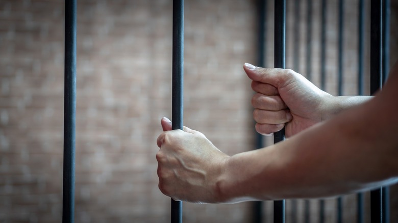 man's hands on jail bars