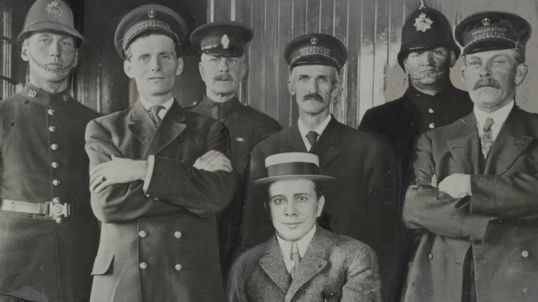 Harry Thaw sitting in suit and hat with police officers