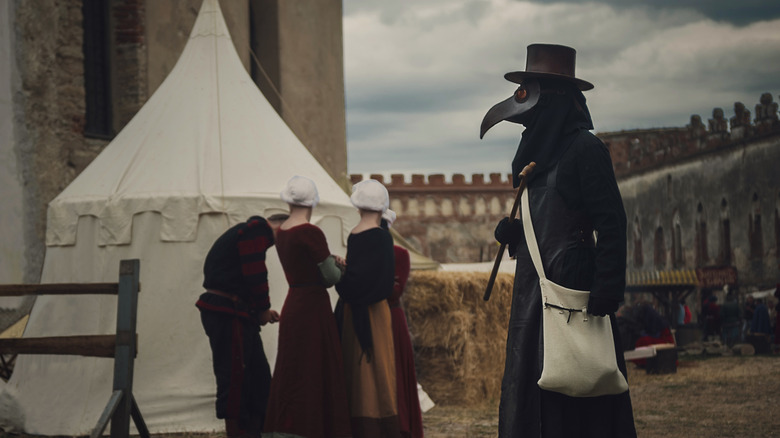 Plague doctor in medieval town 