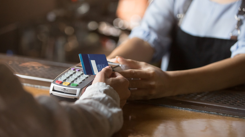 hand with a credit card at a cashier station