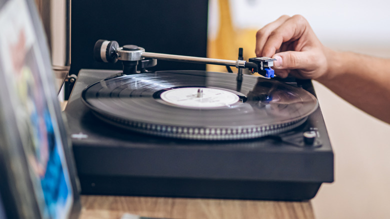 A tonearm sits on a vinyl record