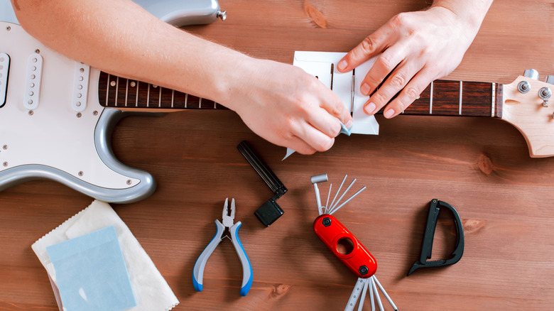 Person cleaning guitar with cleaning kit