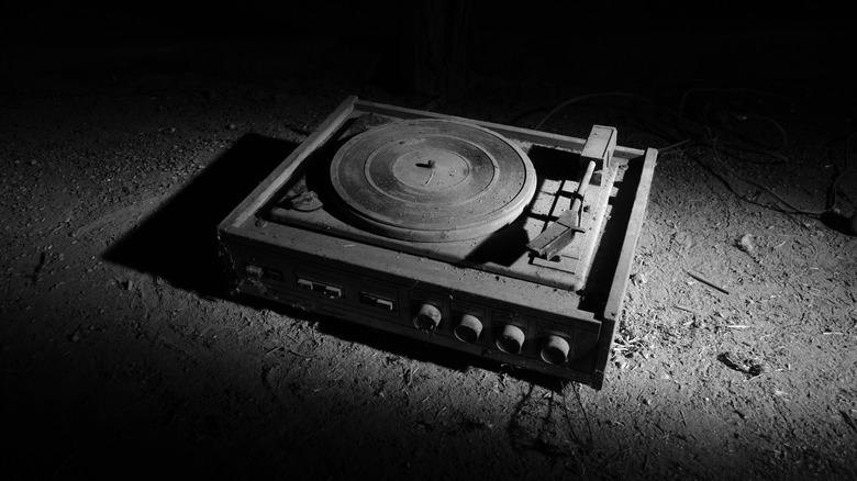 A very dusty turntable placed on ground