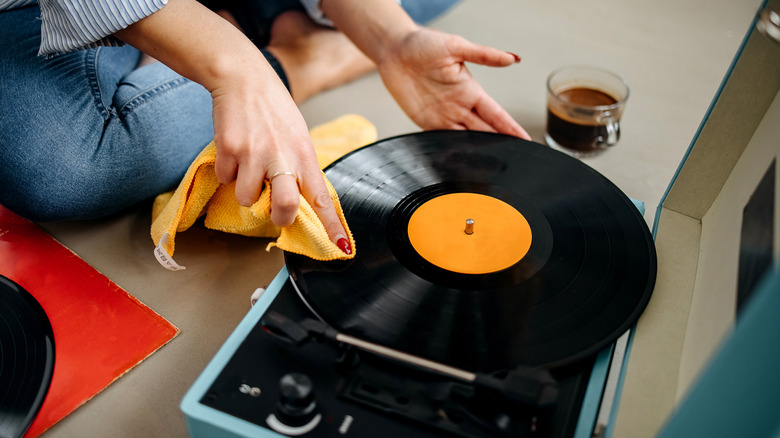 A woman cleans a record on a record player