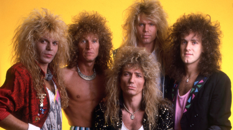 Whitesnake posing together in '80s hair metal dress yellow background