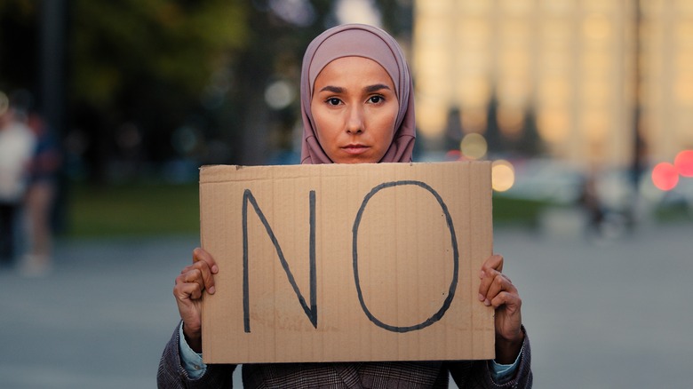 muslim woman holding protest sign