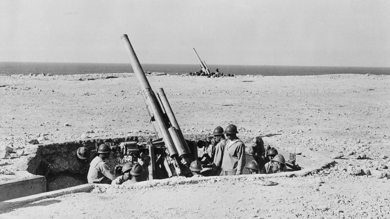 Italian guns and soldiers in pits on a beach in Libya