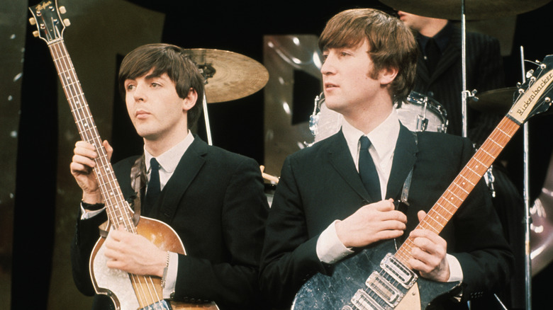 Paul McCartney and John Lennon hold instruments at The Ed Sullivan Show