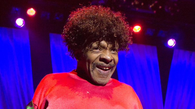 sly stone in red shirt smiling