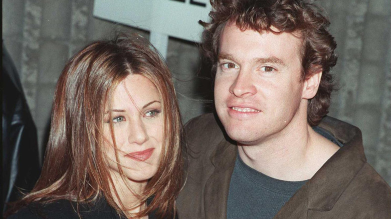 Jennifer Aniston looking off and Tate Donovan smirking