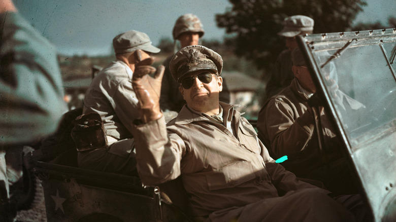 douglas macarthur and other soldiers riding in jeep