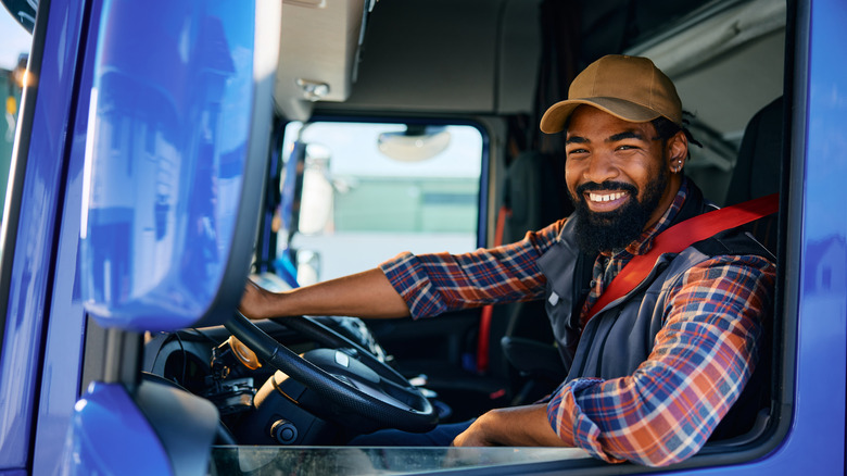 Happy looking truck driver sitting in the semi-truck cabin
