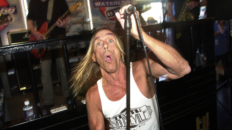 Iggy Pop holding microphone with mouth open