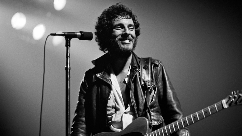 Bruce Springsteen standing onstage at mic smiling
